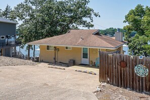 A single-story house with a sloped roof, a front porch, and a wooden fence with a compass and solar panel. - Hot Tub, Large Dock, Fire Pit: Ozarks Lake House (Gravois Mills)