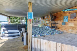 A wooden cabin with a bed, a small table, and a sign for 'Landshark Lager Quality'. - Hot Tub, Large Dock, Fire Pit: Ozarks Lake House (Gravois Mills)