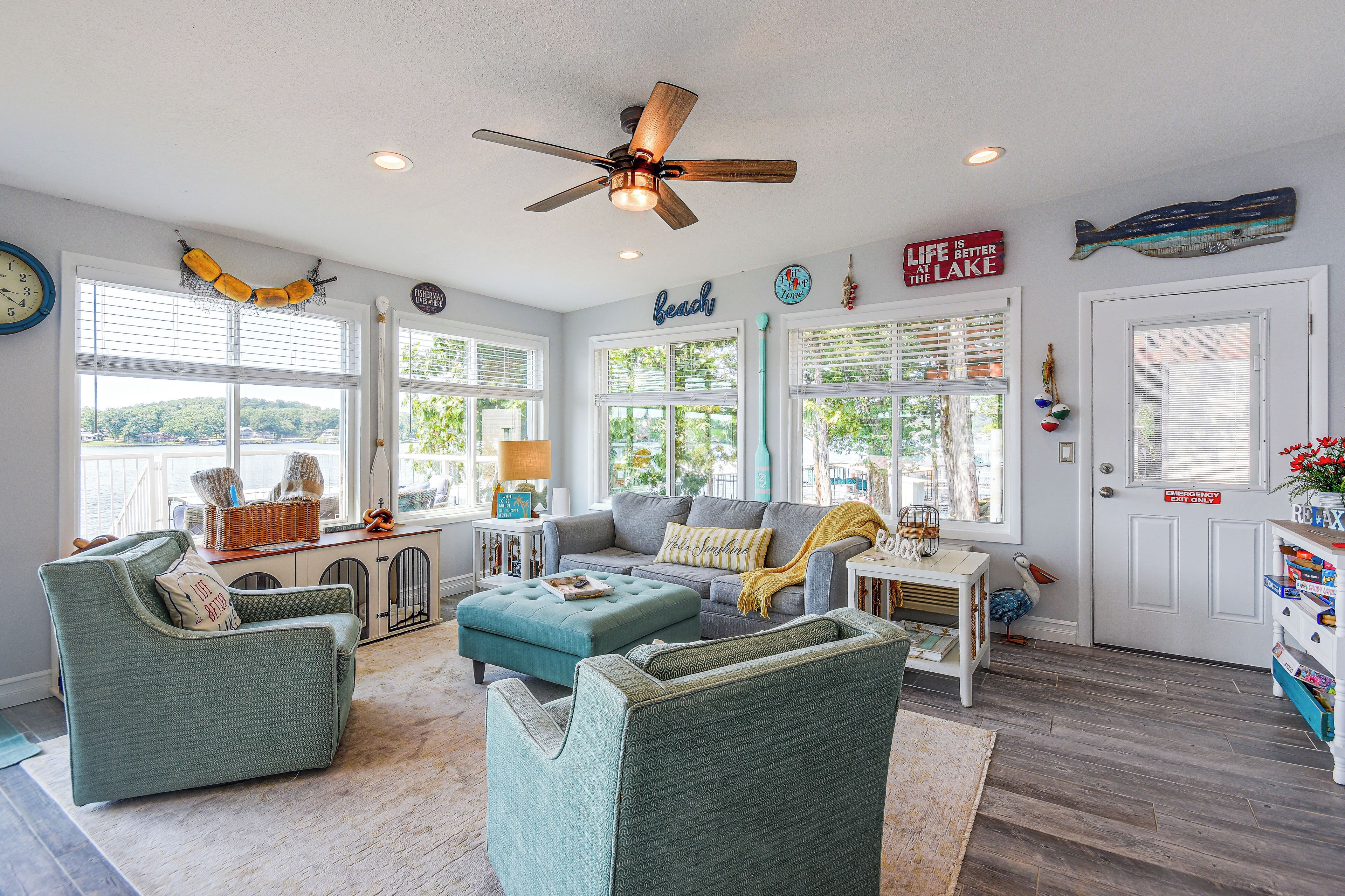 A spacious living room with a ceiling fan, large windows, and a view of the outdoors.