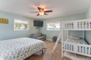 Ein Schlafzimmer mit Etagenbetten, Deckenventilator, Fernseher und einem Fenster mit Jalousien.