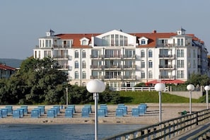 Ein mehrstöckiges Hotel mit Balkonen, einem Poolbereich und einer Strandlage.