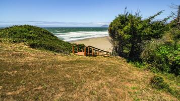 A wooden staircase leading down to a beach with ocean views.