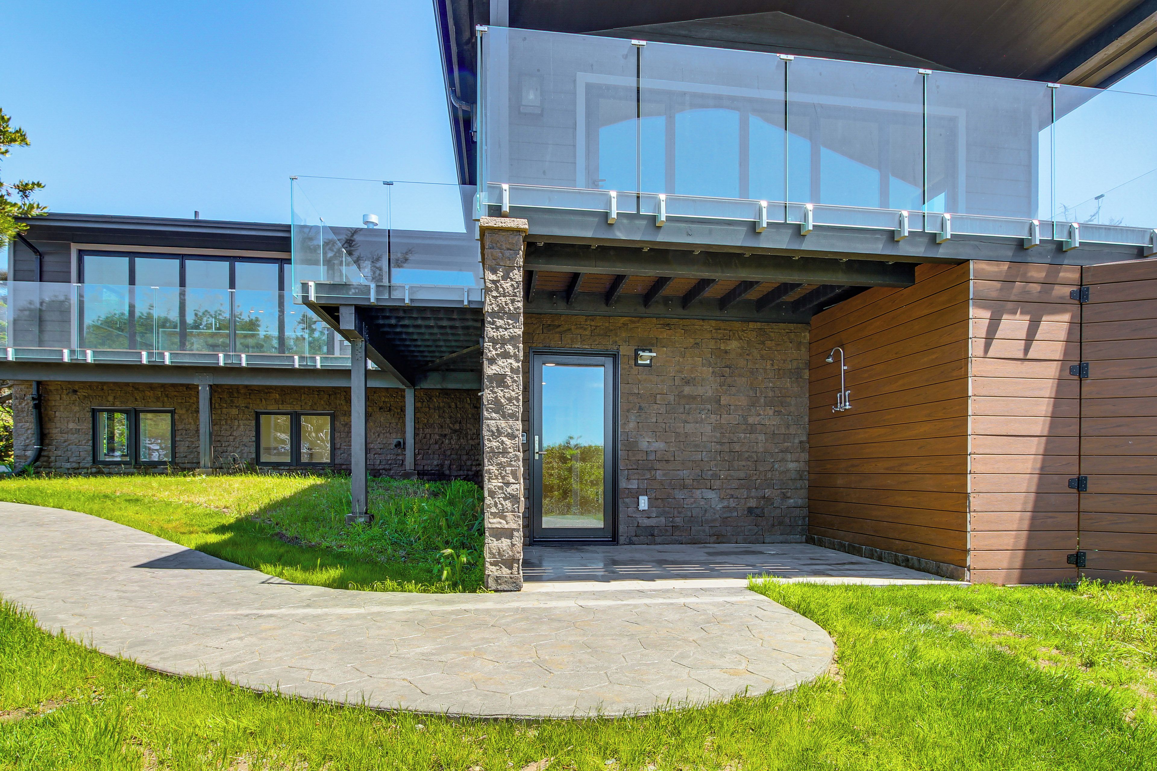 A modern building with a glass balcony, stone facade, and a wooden panel wall.