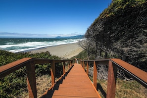 A wooden staircase leading to a beach with ocean views.