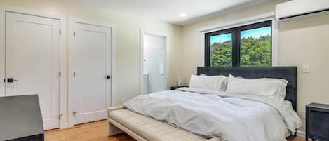 Un dormitorio con cama, banco, armario y equipo de aire acondicionado.