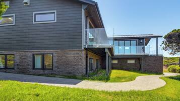A modern two-story house with a stone facade, large windows, and a covered outdoor area.