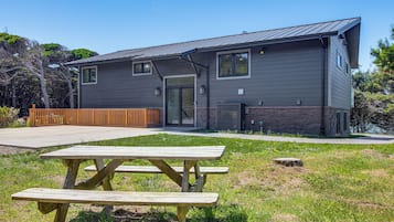 A modern two-story building with a flat roof, a front door, and a small porch area.