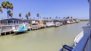 A waterfront property with multiple docked boats, a series of connected houses, and palm trees. - Private Dock, Pool Access: Oceanfront Cottage (Port Isabel)