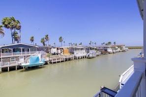 A waterfront property with multiple docked boats, a series of connected houses, and palm trees. - Private Dock, Pool Access: Oceanfront Cottage (Port Isabel)