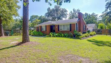 A single-story brick house with a front yard, a tree, and a fence.