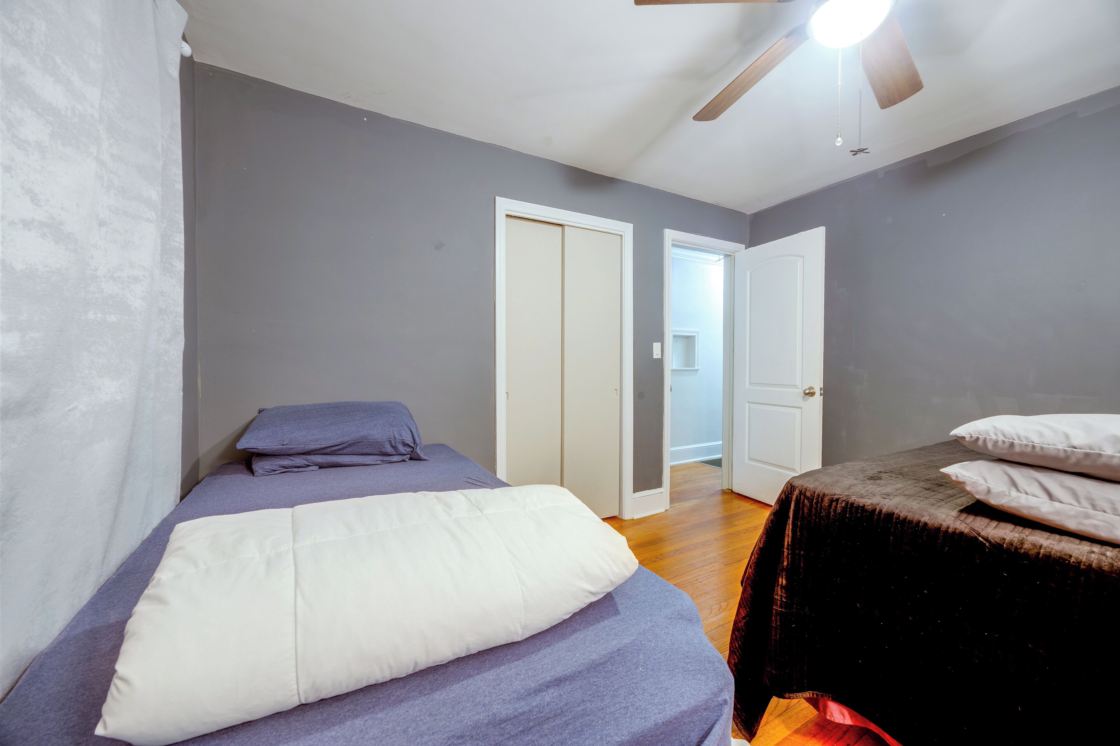 A bedroom with a bed, a ceiling fan, and two doors.