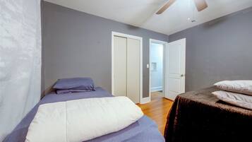 A bedroom with a bed, a ceiling fan, and two doors.