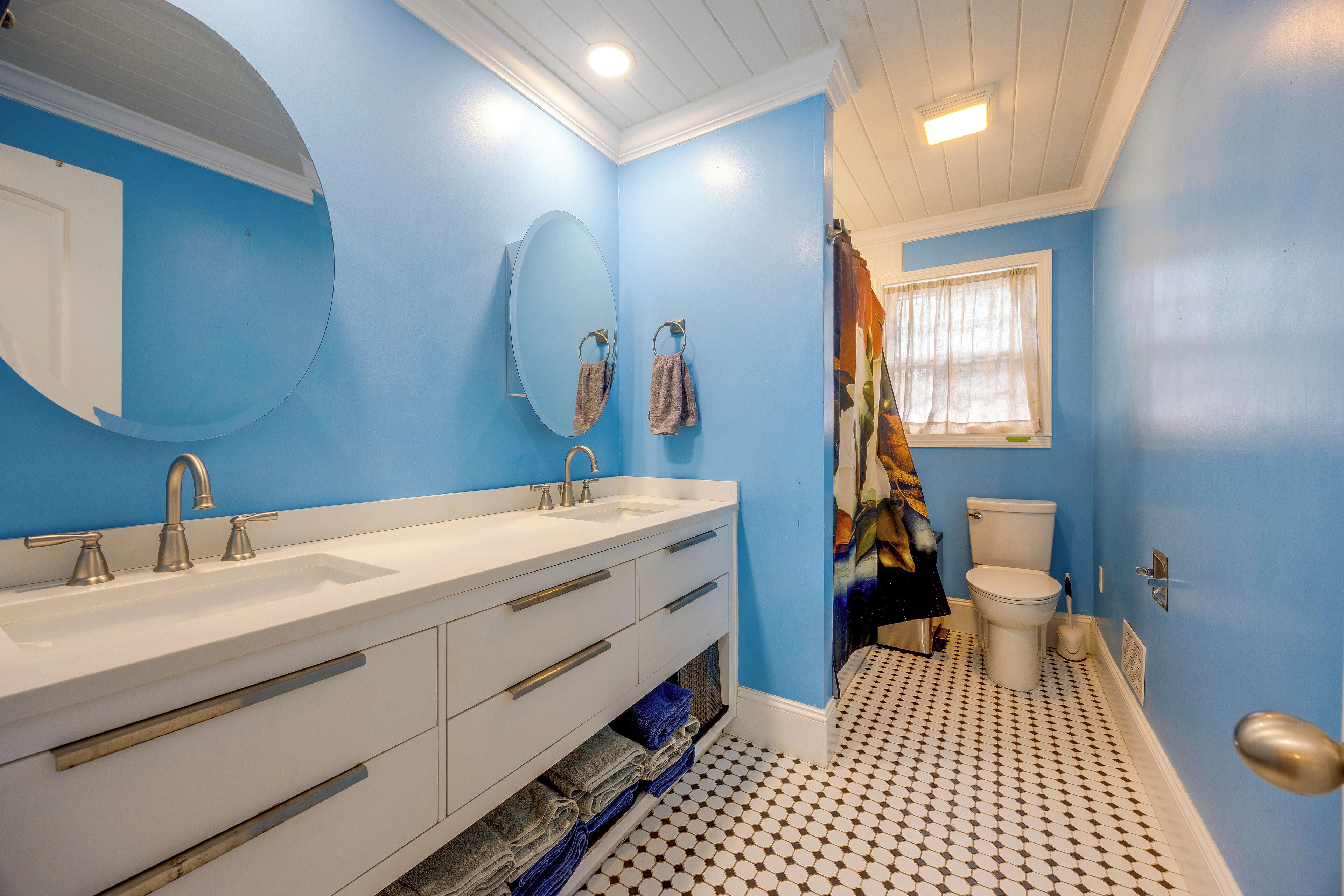 A bathroom with two sinks, a toilet, and a shower curtain.