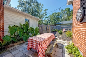 A patio with a checkered tablecloth, a brick wall, and a dartboard.