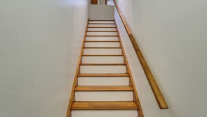 Een houten trap met witte treden die uitkomt op een plateau.
