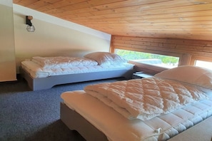 A room with two beds, a window, and a wooden ceiling. - Holiday apartment House Mecklenburg 322202 (Kühlungsborn)