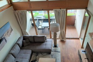 Ett rum med en soffa, ett bord, en lampa och utsikt över omgivningen.