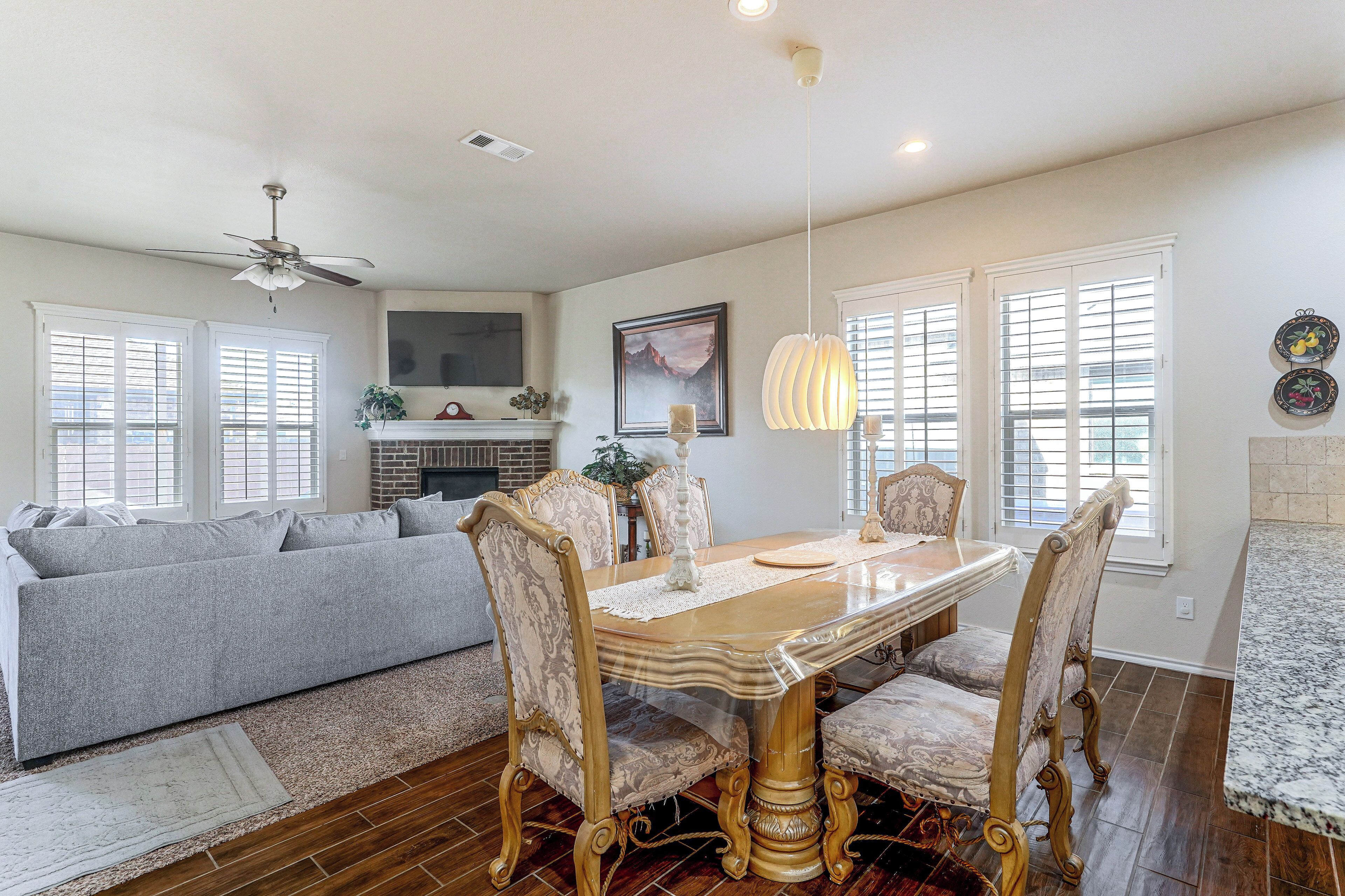 A dining area with a wooden table and chairs, a ceiling fan, and a fireplace.