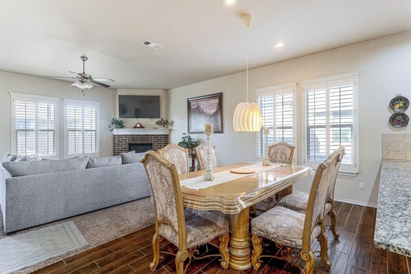 A dining area with a wooden table and chairs, a ceiling fan, and a fireplace.