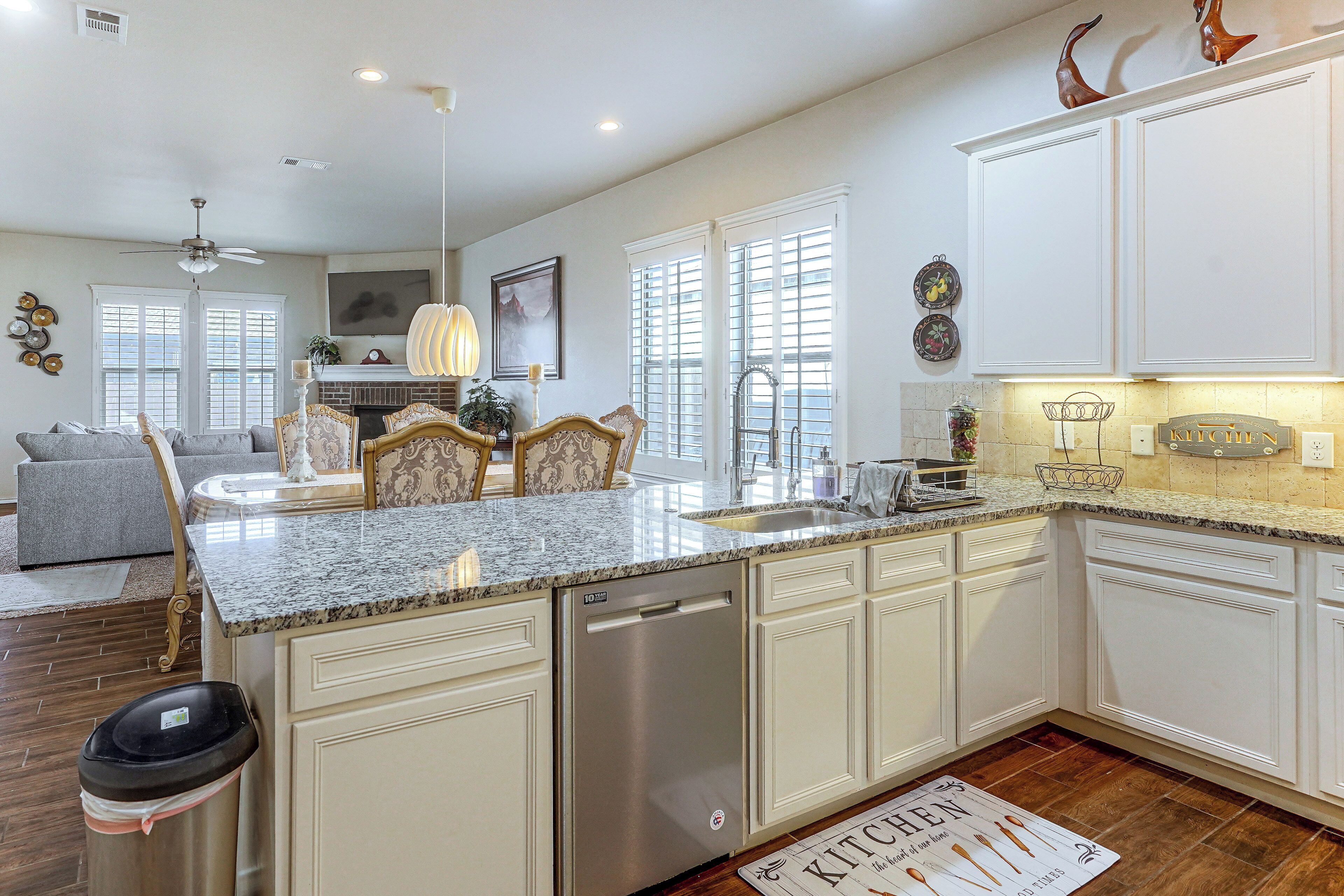 A spacious kitchen with white cabinetry, a granite countertop, and a built-in dishwasher.