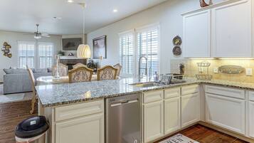 A spacious kitchen with white cabinetry, a granite countertop, and a built-in dishwasher.