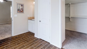 Un pasillo con una puerta blanca, un baño con ducha y suelo alfombrado.