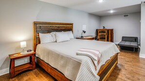 A neatly arranged bedroom with a wooden bed, bedside tables, a desk, and a chair.