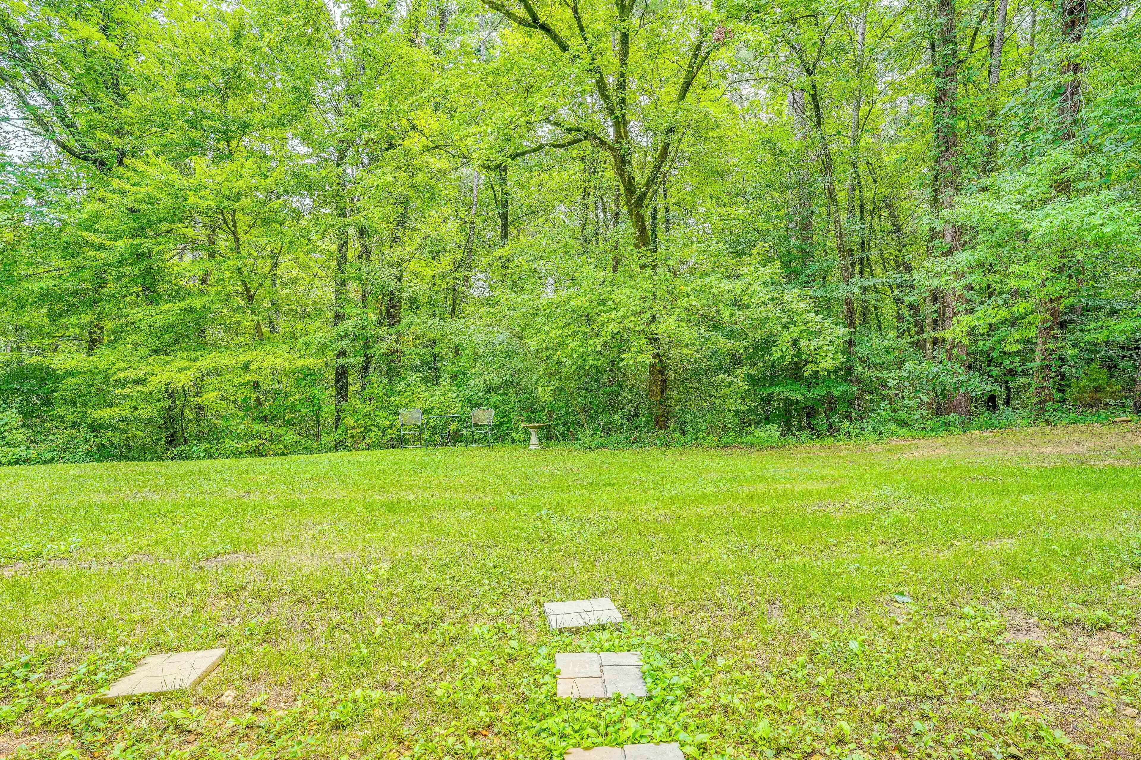 A grassy area with a stone pathway leading through a wooded area.
