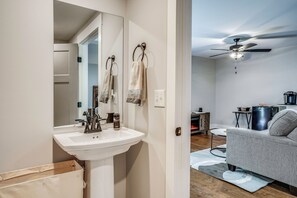 A modern bathroom with a white sink, a mirror, and a ceiling fan.