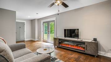 A modern living room with a fireplace, a ceiling fan, and a television.