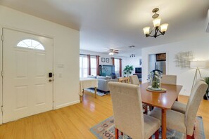 A dining area with a wooden table and chairs, a chandelier, and a view into the living room.