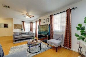 A living room with a sofa, armchair, coffee table, and a fish tank.