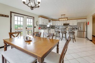 Una cocina moderna con armarios blancos, electrodomésticos de acero inoxidable y una zona de comedor con mesa y sillas de madera.
