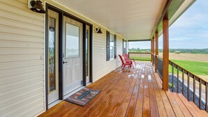 A wooden porch with a red chair, a welcome mat, and a view of the countryside. - Game Room & Countryside Views! Salvisa Family Gem (Salvisa)