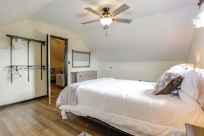 A bedroom with a bed, a ceiling fan, a dresser, and a mirror.