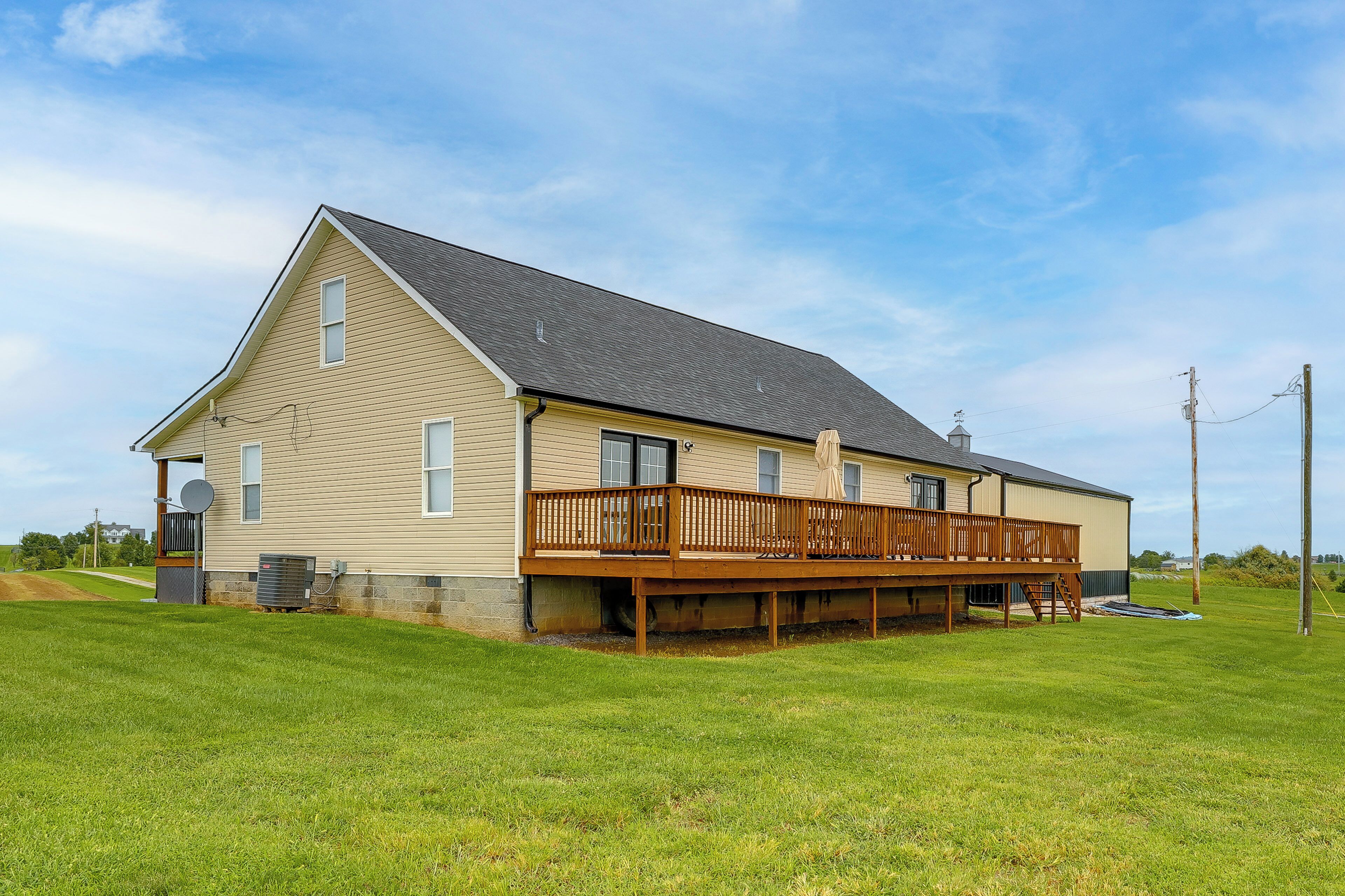 A single-story house with a wooden deck, a garage, and a large front lawn.