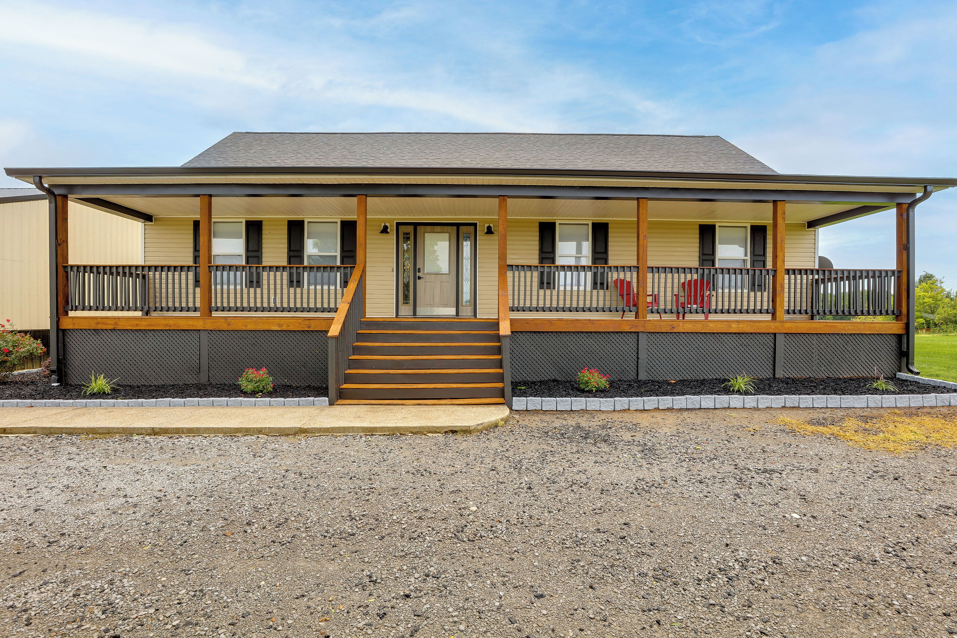 A two-story motel with a covered front porch, a staircase leading to the entrance, and a gravel driveway.