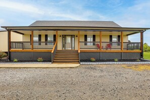 A two-story motel with a covered front porch, a staircase leading to the entrance, and a gravel driveway. - Game Room & Countryside Views! Salvisa Family Gem (Salvisa)