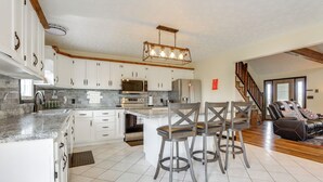 A spacious kitchen with white cabinets, stainless steel appliances, and a central island with bar stools. - Game Room & Countryside Views! Salvisa Family Gem (Salvisa)