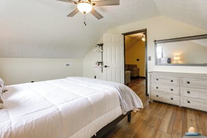 Un dormitorio con cama, cómoda y ventilador de techo.