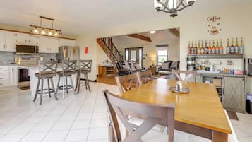 A spacious kitchen with modern appliances, a dining area with wooden furniture, and a bar area with a coffee theme.