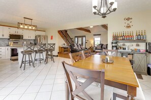 A spacious kitchen with modern appliances, a dining area with wooden furniture, and a bar area with a coffee theme.