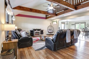 A spacious living room with leather sofas, a fireplace, and a ceiling fan.
