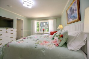 A bedroom with a bed, a television, a window with curtains, a painting on the wall, and a dresser. - Office, Deck, Yard: Thomasville Gem on Golf Course (Thomasville)