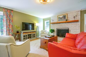 A living room with a fireplace, a television, and a red sofa.