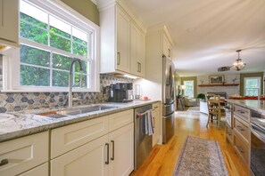 A modern kitchen with a large window, stainless steel appliances, and a herringbone tile backsplash.