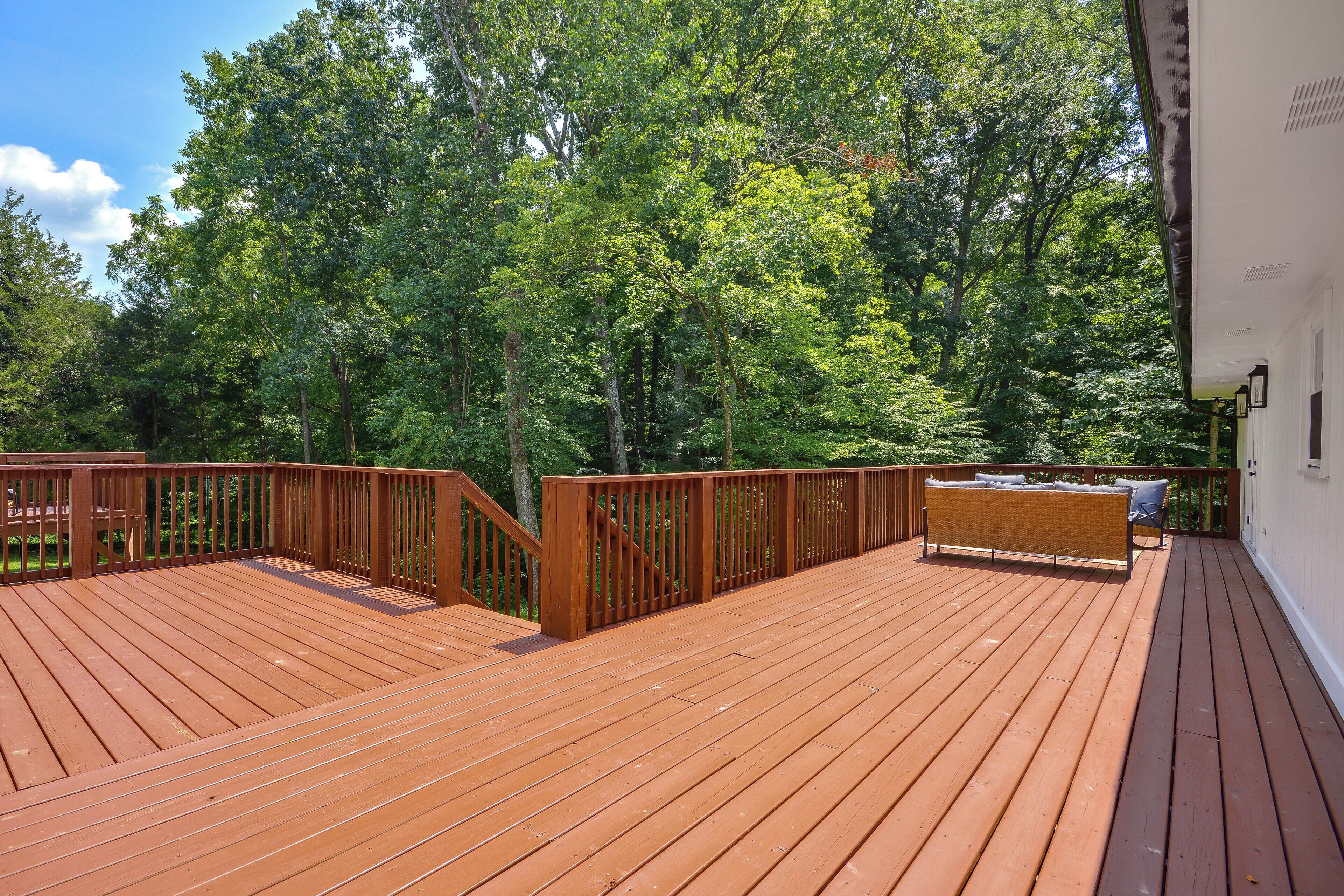 Una terraza de madera con barandilla, rodeada de árboles.