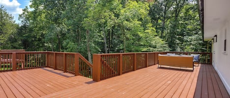A wooden deck with a railing, surrounded by trees.