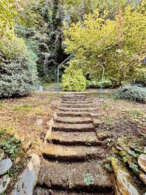 A stone staircase leading up to a covered area surrounded by dense foliage. - Maison de campagne à Cuneo (Villa)