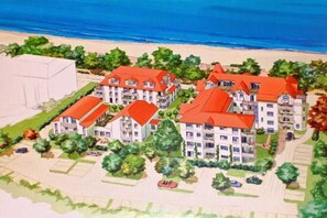 Ein Hotel an der Küste mit mehreren Gebäuden, einem Parkplatz und Blick auf den Strand.